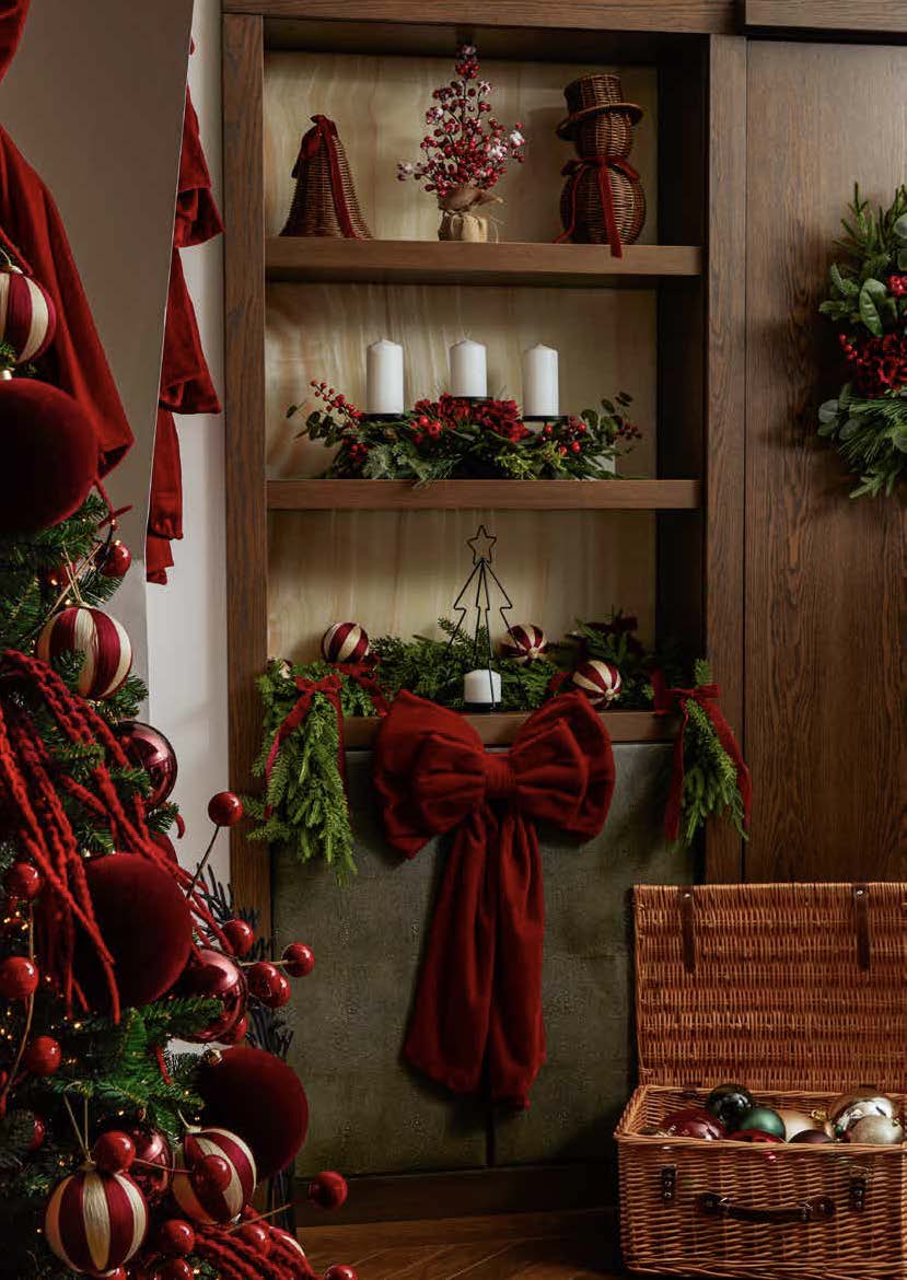 A red Christmas bow and greenery decorating wooden shelves