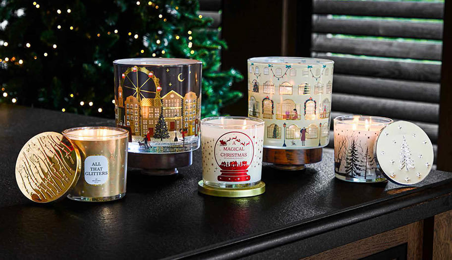 Festive scented candles beside a twinkling Christmas tree