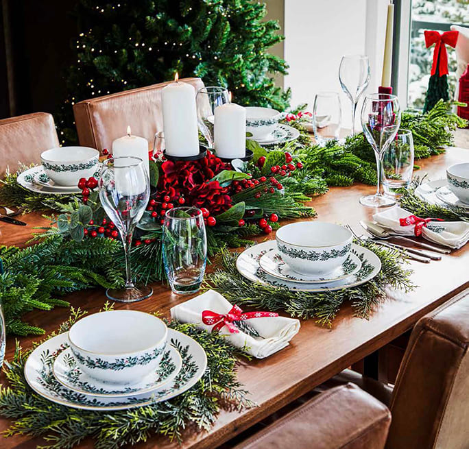 A Christmas dining table with festive greenery and traditional tableware